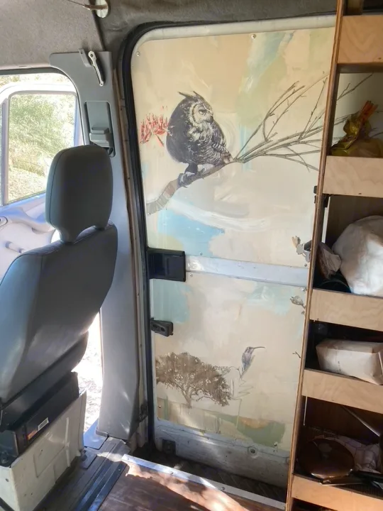 An RV rental's custom interior panel features beautiful paintings of an owl, hummingbird, and trees, enhancing its unique charm.. Dodge Sprinter 2003