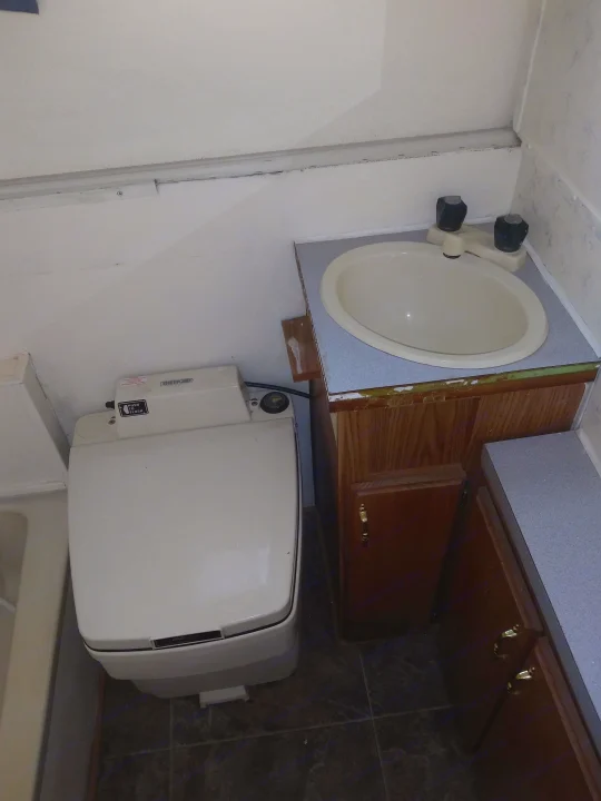 RV rental bathroom: Compact space with a white sink, Thetford toilet, and wooden cabinets, ideal for travel.. K-Z Manufacturing Coyote 2002