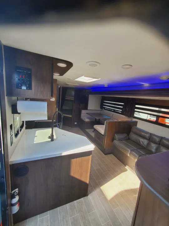 Modern RV rental interior: kitchenette, dinette, sofa, and bunk beds with wood-look accents and blue LED lighting.. Forest River Cherokee Grey Wolf 2021