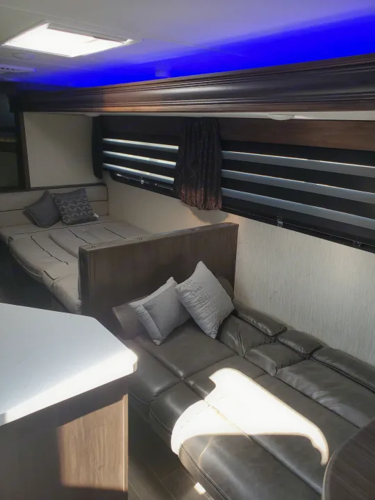 Modern RV rental interior features blue ambient lighting, a skylight, and inviting bed/sofa seating.. Forest River Cherokee Grey Wolf 2021