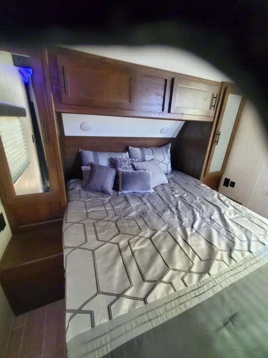 Compact and modern RV rental bedroom featuring a grey bed, overhead storage, and integrated lighting.. Forest River Cherokee Grey Wolf 2021