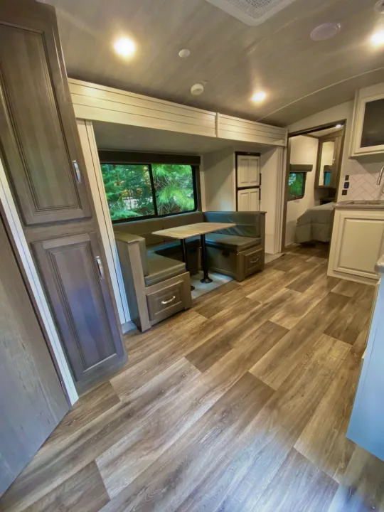 Bright RV rental interior: a dinette with large window views, wood floors, and a well-equipped kitchen.. Keystone Cougar Half-Ton 2022