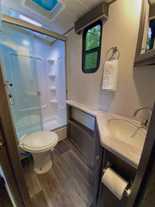Clean, well-appointed RV rental bathroom featuring a compact shower, toilet, and modern vanity with sink.. Keystone Cougar Half-Ton 2022
