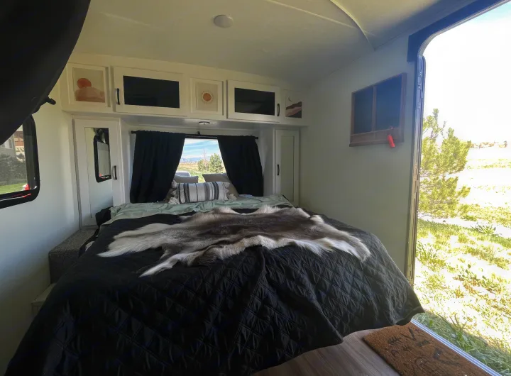 Plush RV rental bedroom with a queen bed, cozy faux fur, modern overhead cabinets, and scenic window views.. Forest River Coachmen Apex Nano Off-Grid 2022