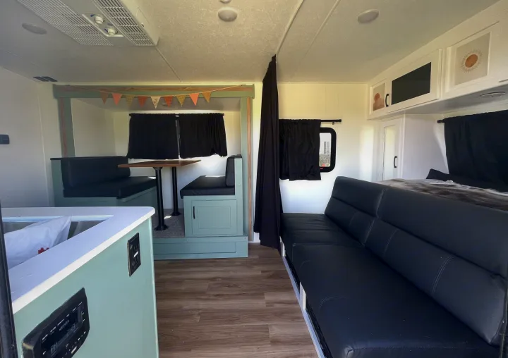 Bright, renovated RV rental interior featuring a teal dinette, black sofa, kitchen counter, and bed. Ideal for travel.. Forest River Coachmen Apex Nano Off-Grid 2022
