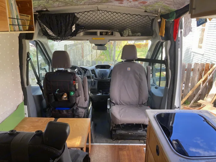 Interior of an RV rental camper van, featuring a cozy custom build with front seats, storage, and a sink, from rear view.. Ford Transit Custom 2015