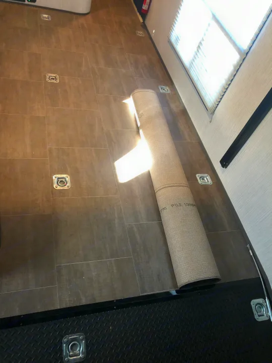 RV rental toy hauler interior: Tiled floor with secure tie-downs and a rolled rug. Bright, adaptable mobile space.. Cruiser Rv Corp Stryker 2020