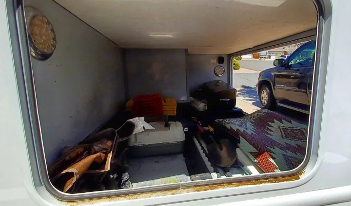 Spacious RV rental storage bay reveals a BBQ grill, shovel, patterned rug, and various travel essentials.. Thor Majestic 2015