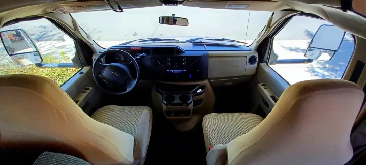 RV rental interior: Wide shot of the Ford RV cab from behind, showing steering wheel, dashboard, and front seats.. Thor Majestic 2015