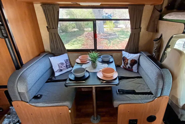 Enjoy meals in this comfy RV rental dining area. Features a dinette, window views, and set table.. Thor Majestic 2015