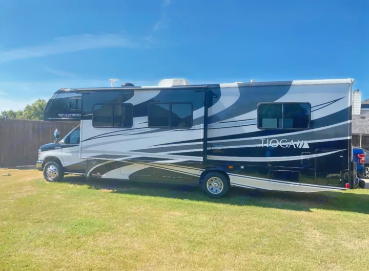 Explore in comfort: a sleek black, white, and gray Fleetwood Tioga Class C RV rental, parked on green grass under a blue sky.. Tioga Tioga Motorhome 2012