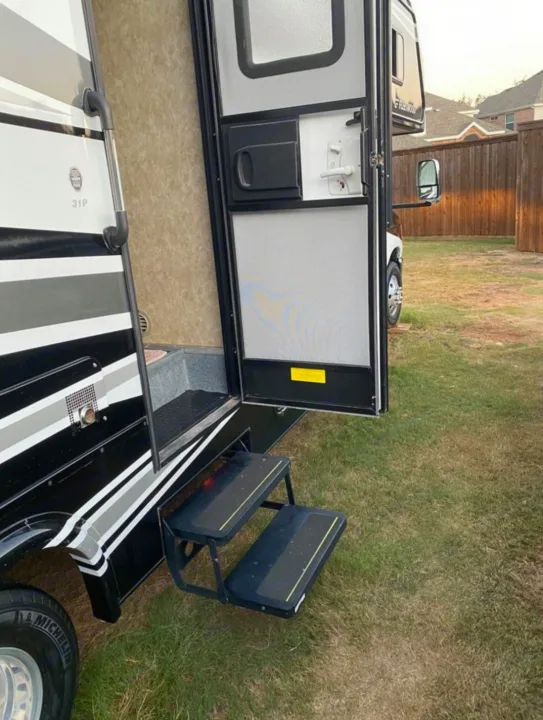 Side view of an RV rental with an open main door, screen door, and two extended steps for easy entry on a grassy lawn.. Tioga Tioga Motorhome 2012