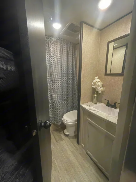 Compact RV rental bathroom with a modern grey and white interior, featuring a shower, toilet, and vanity with sink and mirror.. Jayco JAYCO JAY FLIGHT SLX 264BH 2022