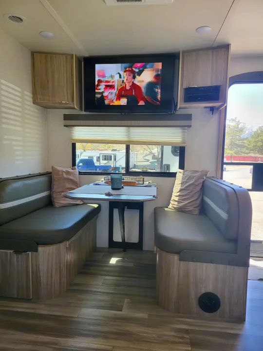 Spacious RV rental dinette and living area with TV, entertainment system, and modern wood finishes.. Winnebago Minnie Winnie 2022