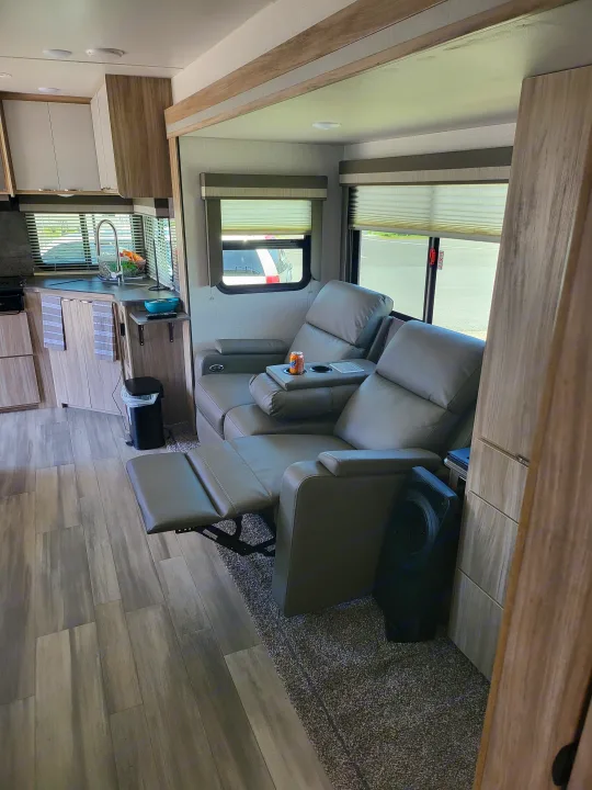 Spacious RV rental interior featuring comfortable reclining seats, a functional kitchen, and stylish wood-look flooring.. Winnebago Minnie Winnie 2022