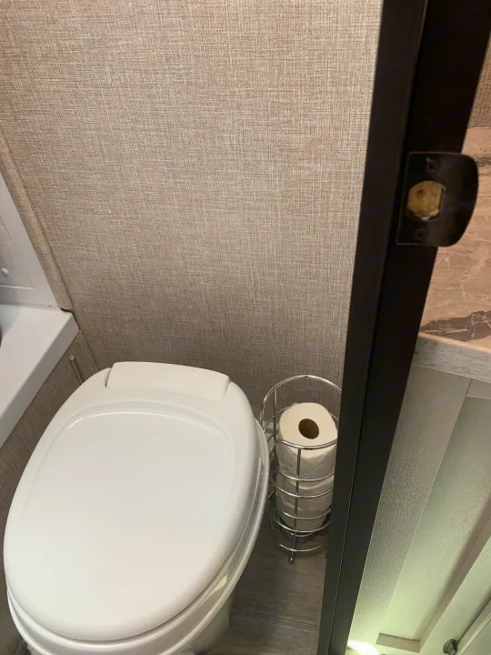 Inside an rv rental, a compact Thetford toilet in a clean, modern bathroom with toilet paper storage.. Jayco Jay Flight 2022