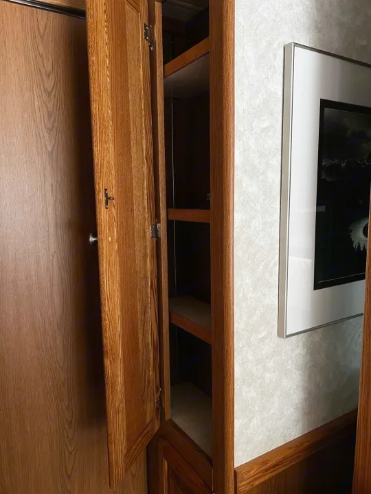 RV rental interior: A wooden cabinet with shelves, adjacent to another wood door, featuring compact storage.. Allegro Allegro Bay 2004
