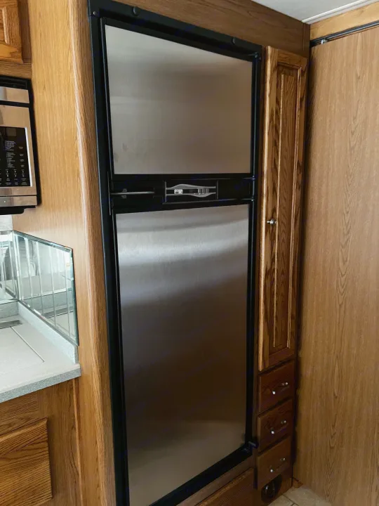Inside an RV rental: modern kitchen area featuring a stainless steel refrigerator, microwave, and wood cabinets.. Allegro Allegro Bay 2004