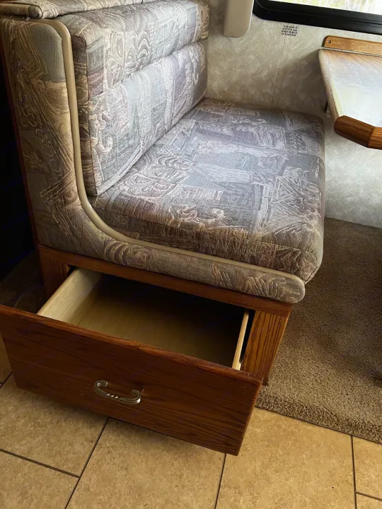 Upholstered RV rental bench seat with an open storage drawer, showing practical interior design.. Allegro Allegro Bay 2004