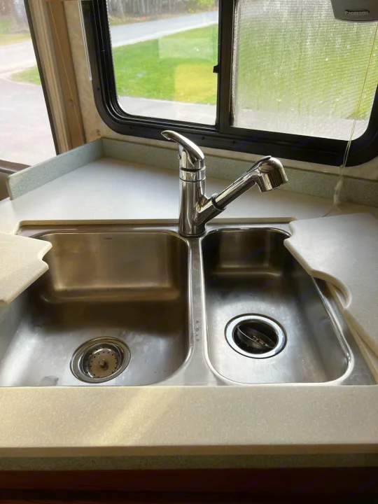 RV rental kitchen: Dual stainless steel sink with modern pull-down faucet, clean countertops, and window view. Ideal for travel.. Allegro Allegro Bay 2004