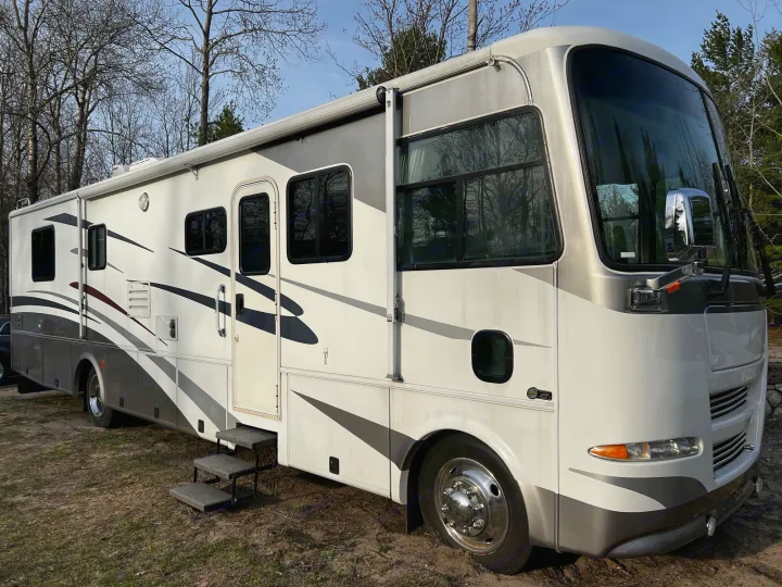 Experience nature with this spacious white and grey RV rental. Motorhome parked outdoors with trees in the background.. Allegro Allegro Bay 2004