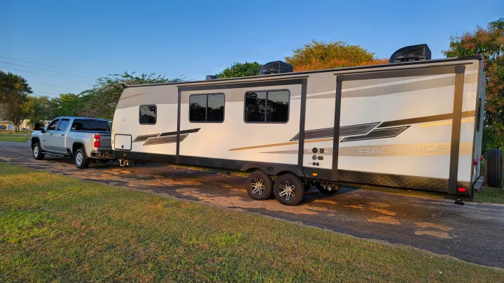 Planning an RV rental? This large travel trailer is seen hitched to a silver pickup truck, ready for towing.. Cruiser Rv Corp Radiance 30ds 2021