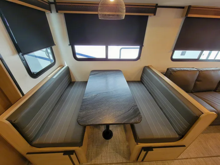 Bright RV rental dinette area featuring dark grey cushioned benches, a patterned table, and windows with blinds.. Cruiser Rv Corp Radiance 30ds 2021