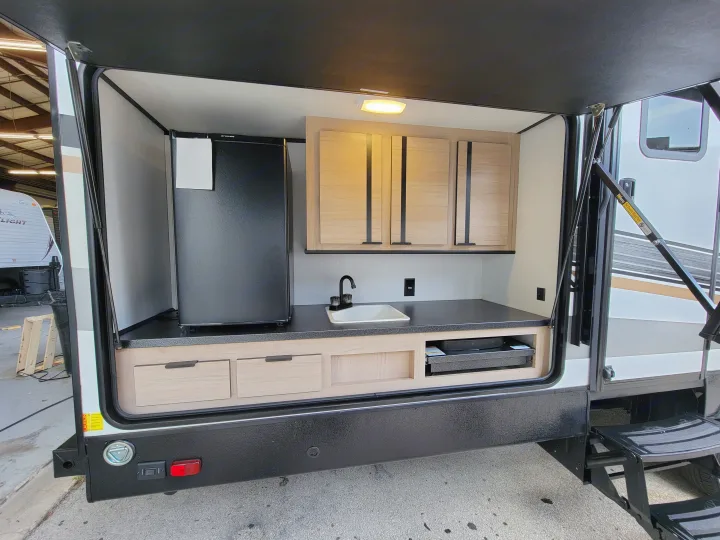 This RV rental's outdoor kitchen features a fridge, sink, cabinets, countertop, and pull-out grill for convenient camping meals.. Cruiser Rv Corp Radiance 30ds 2021