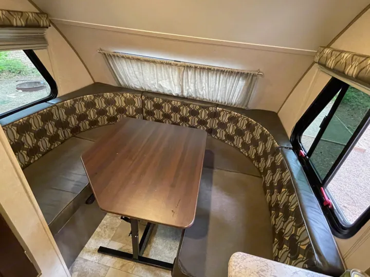 RV rental dinette with U-shaped patterned seating and a wooden table, offering a cozy interior space.. R-Pod Hood River Edition 2017