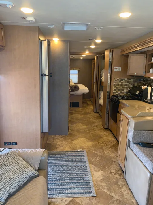 Spacious RV rental interior with living area, kitchen, bedroom, and bunk beds. Brightly lit and ready for travel.. Thor Windsport 2017
