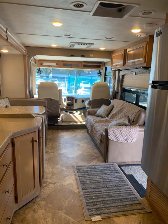 Inside a comfortable rv rental: a view from the kitchen through the living room to the driver's cabin with dual seats.. Thor Windsport 2017