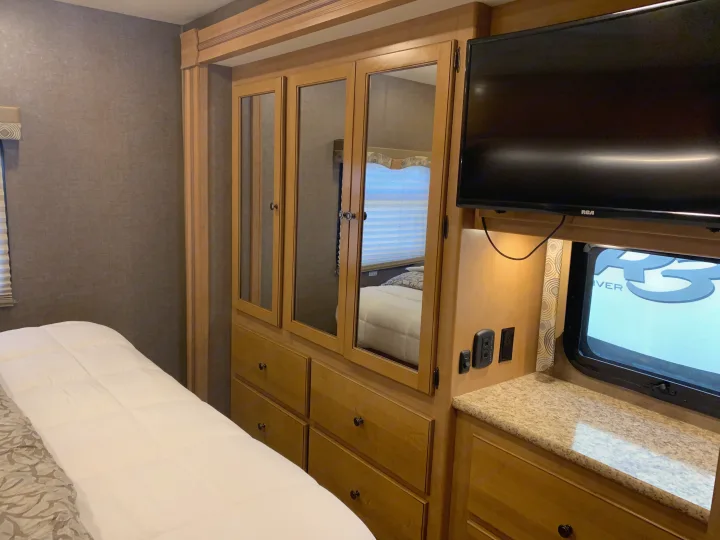 Inside an RV rental: a cozy bedroom with a bed, mirrored wardrobe, TV, and counter. Ideal for compact living.. Thor Windsport 2017