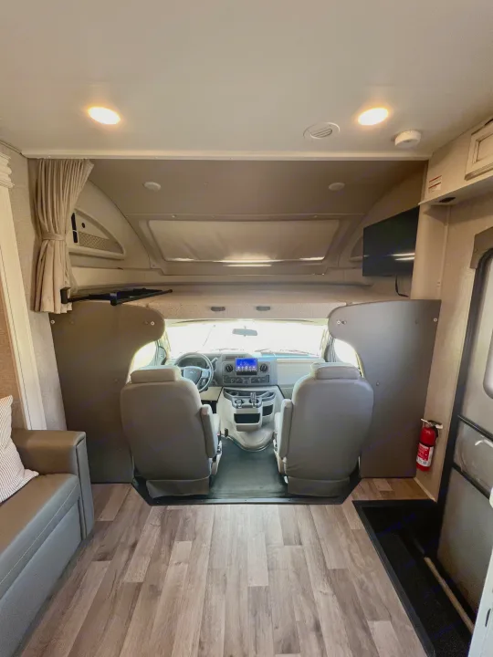Spacious RV rental interior featuring the driver's cabin, front seating, and overhead sleeping area.. Entegra Coach Odyssey 2021