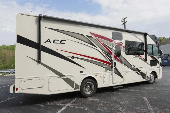 This RV rental, a white ACE model with red & black graphics, is parked on asphalt, ready for adventure.. Thor Motor Coach A.C.E 2022