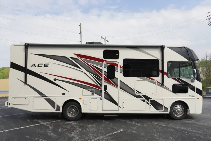 Spacious Class A RV rental with modern black, grey, and red graphics, parked on asphalt, ready for adventure.. Thor Motor Coach A.C.E 2022