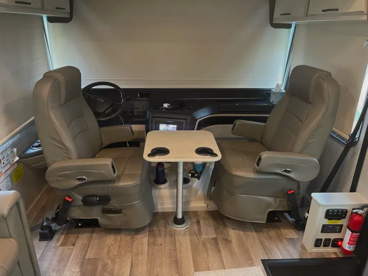 Spacious RV rental cockpit featuring two comfortable captain's chairs, a removable table, and essential driver controls.. Jayco Precept 2021