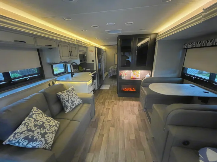 Cozy RV rental interior showcasing a kitchen, living area, dining booth, and fireplace. Ready for travel.. Jayco Precept 2021