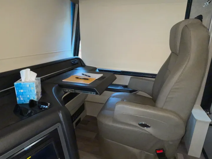 RV rental: Cozy interior featuring a grey captain's chair with a pull-out desk, notebook, pens, tissues, and sunglasses.. Jayco Precept 2021