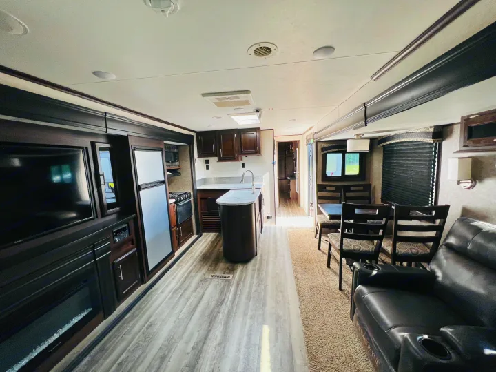 This RV rental interior offers a full kitchen with island, dining area, comfy recliners, and entertainment center.. Jayco Jay Flight 2019