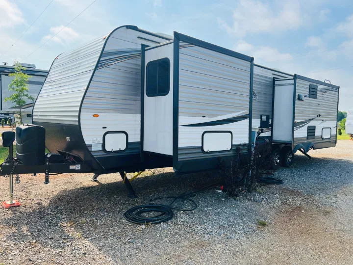 Spacious rv rental travel trailer parked with slide-outs extended at a sunny gravel campsite.. Jayco Jay Flight 2019