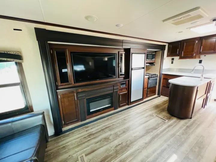 Bright RV rental living space featuring a flat-screen TV, fireplace, full kitchen, and comfortable seating.. Jayco Jay Flight 2019