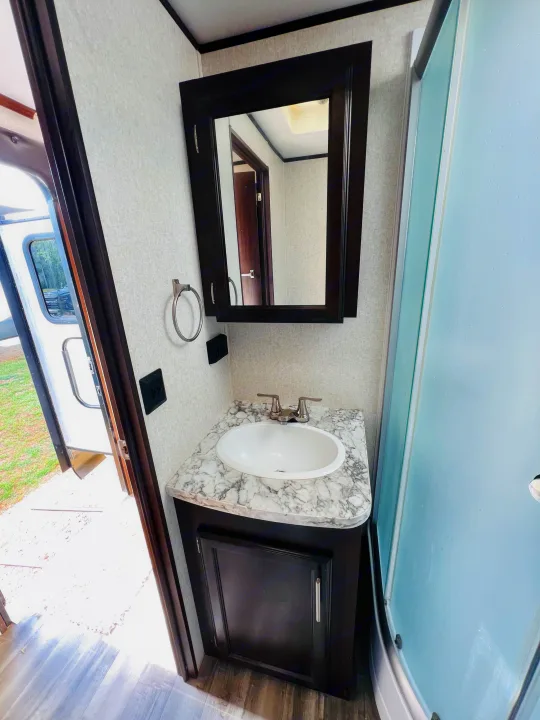 Clean RV rental bathroom with a vanity, sink, mirror, and shower. Bright interior for your travel comfort.. Jayco Jay Flight 2019
