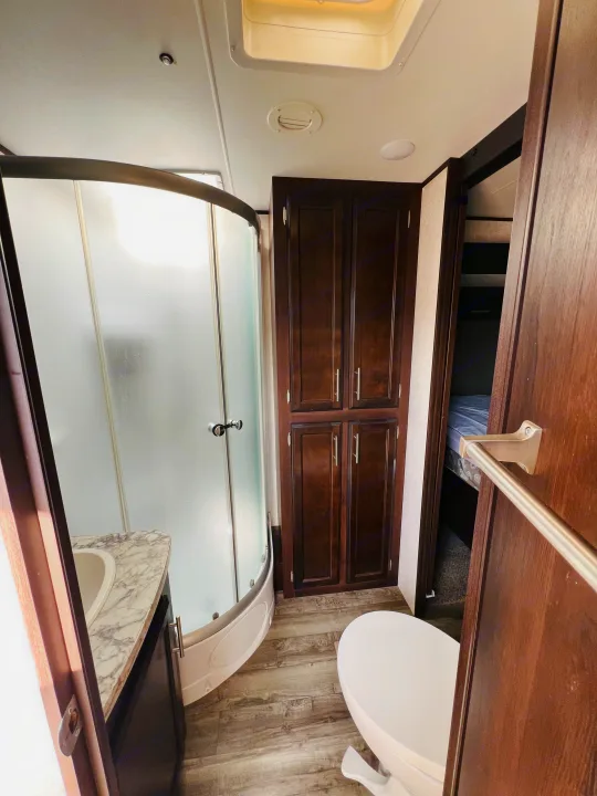 Clean RV rental bathroom showcasing a shower, toilet, sink, and storage cabinets for your travels.. Jayco Jay Flight 2019