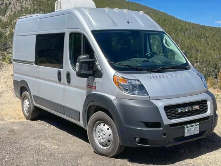 Silver Ram ProMaster camper van parked on a dirt road, mountains in background. Perfect rv rental for your next outdoor adventure.. RAM Promaster ALPINE X Edition OA15 2021