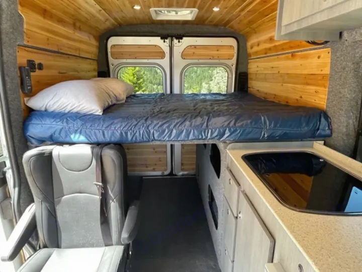 Cozy RV rental interior with elevated bed, kitchen, and seating, perfect for your next road trip adventure.. RAM Promaster ALPINE X Edition OA15 2021