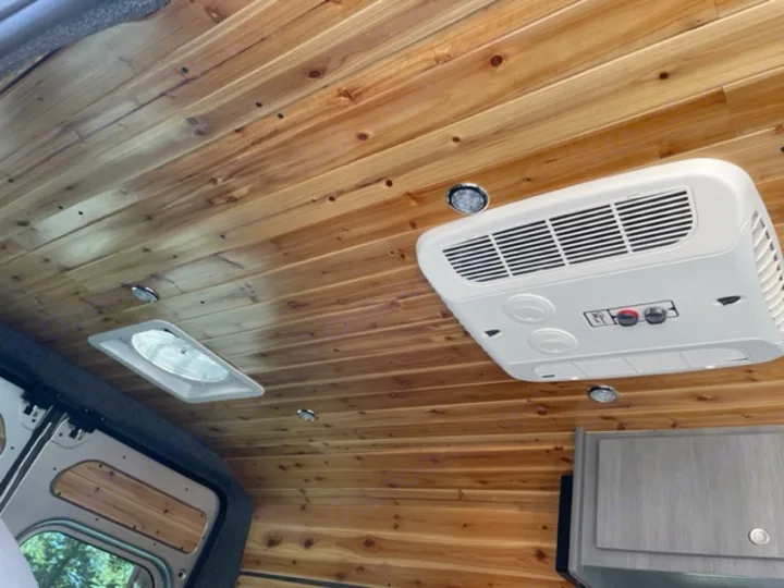 Cozy RV rental interior with a beautiful wood plank ceiling, recessed lights, a roof vent, and an overhead air conditioner unit.. RAM Promaster ALPINE X Edition OA15 2021