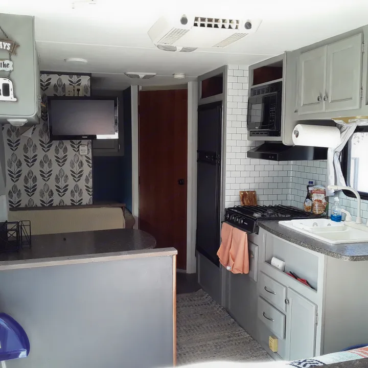 Modern RV rental kitchen with grey cabinets, subway tile, and dining area.. Heartland RVs Trail Runner 2013