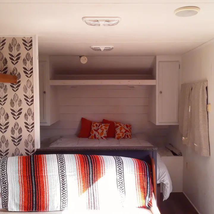 Step inside this cozy RV rental's bedroom, featuring a vibrant bed with colorful pillows & patterned wallpaper.. Heartland RVs Trail Runner 2013