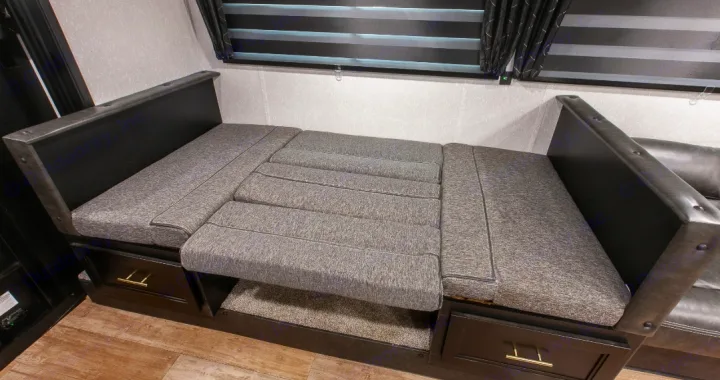 RV rental's gray convertible dinette/sofa bed, featuring storage drawers.. Forest River Cherokee Grey Wolf 2022