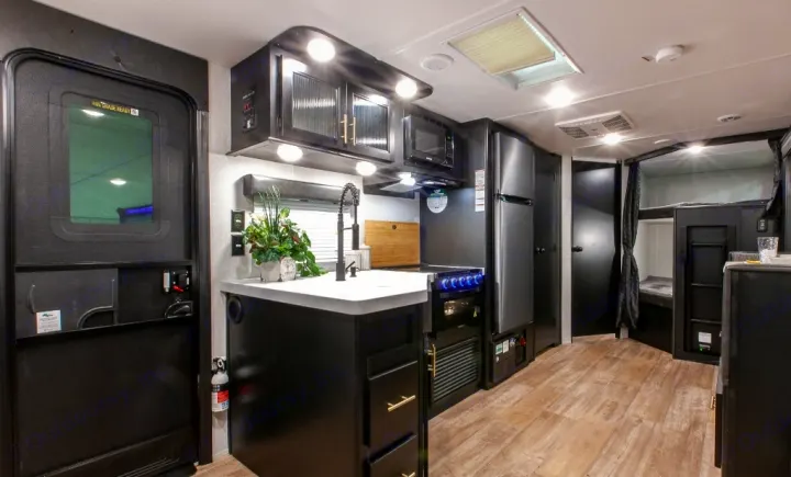 This RV rental interior features a sleek, well-equipped kitchen, refrigerator, and bunk beds, offering comfortable living space.. Forest River Cherokee Grey Wolf 2022